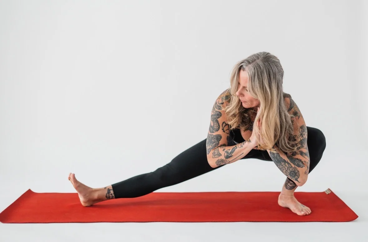 Jennifer Dessert practicing a side lunge on a red yoga mat.