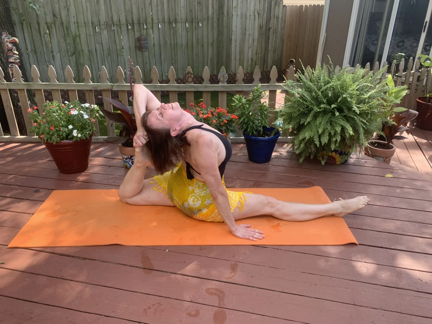 Shari practicing yoga on an outdoor mat surrounded by plants.