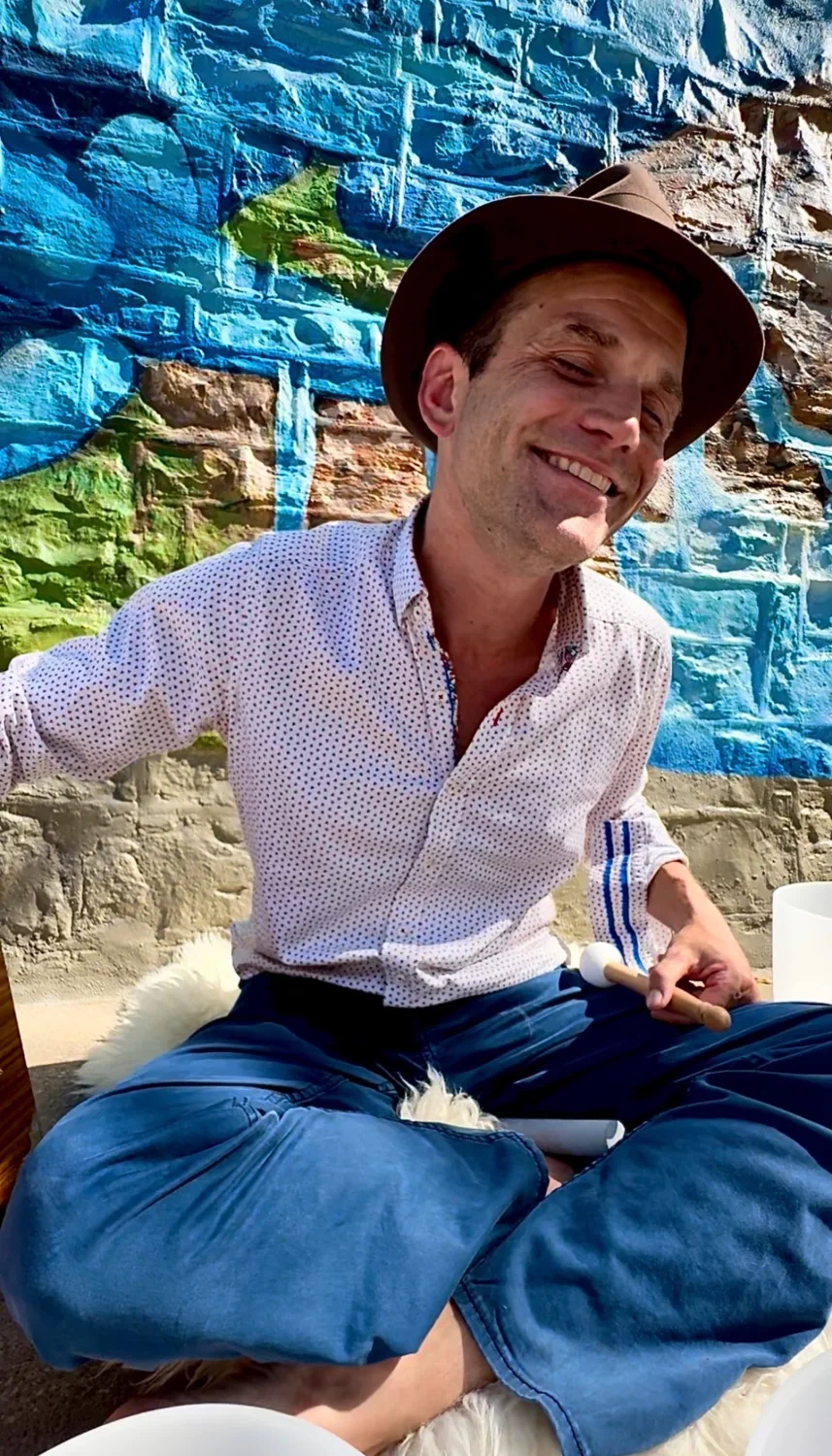 Shawn Lillig seated with a mallet beside sound bowls.